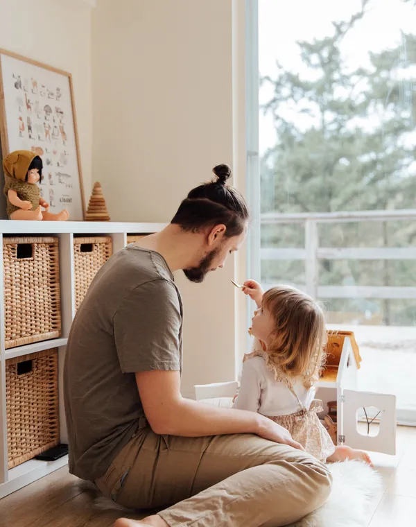 Un papa assis par terre partage un moment complice avec sa petite fille
