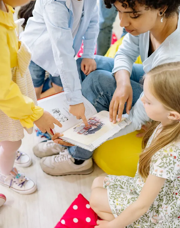 Une animatrice lit un livre illustré à un groupe d’enfants