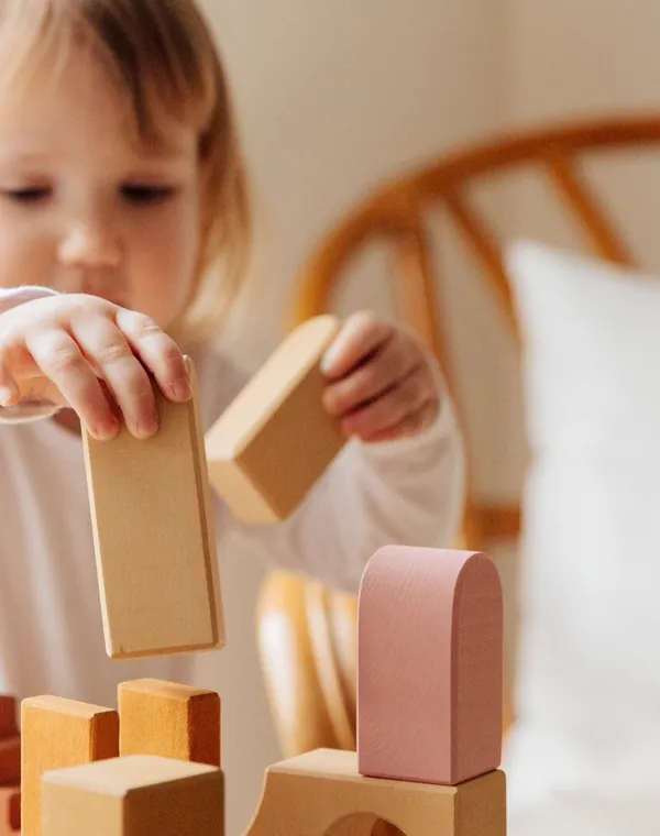 Un tout-petit concentré construit une tour de cubes en bois