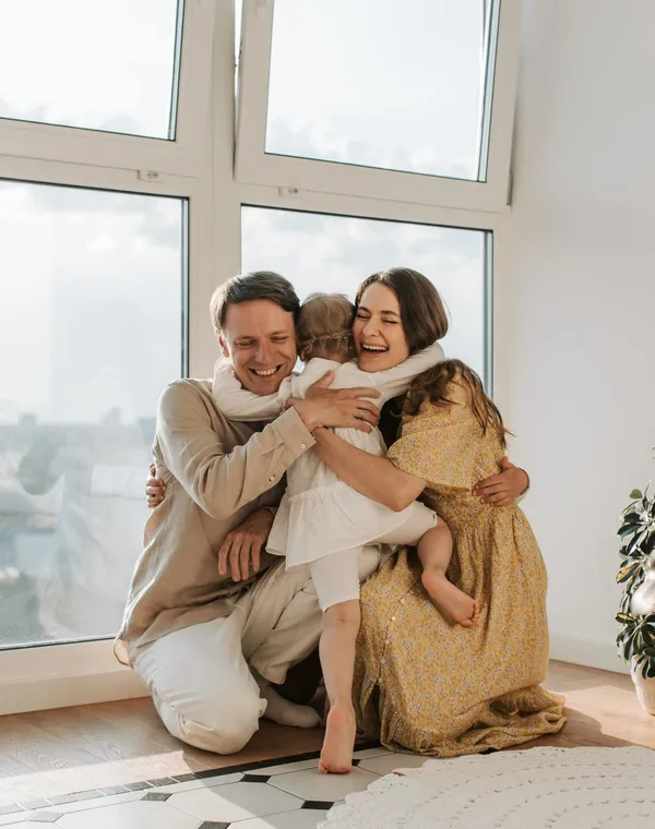 Des parents et leur fille réunis dans un câlin plein de rires